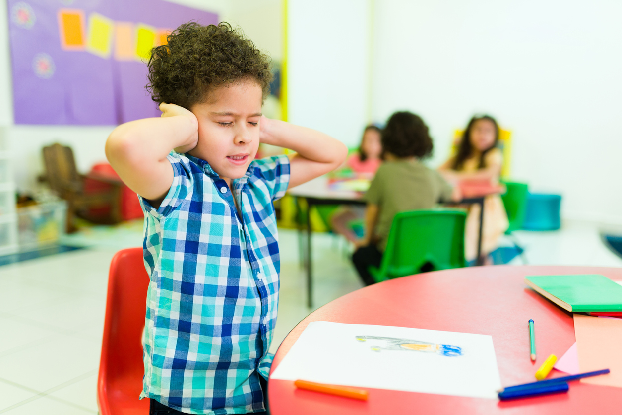 Upset autistic young boy covering his ears