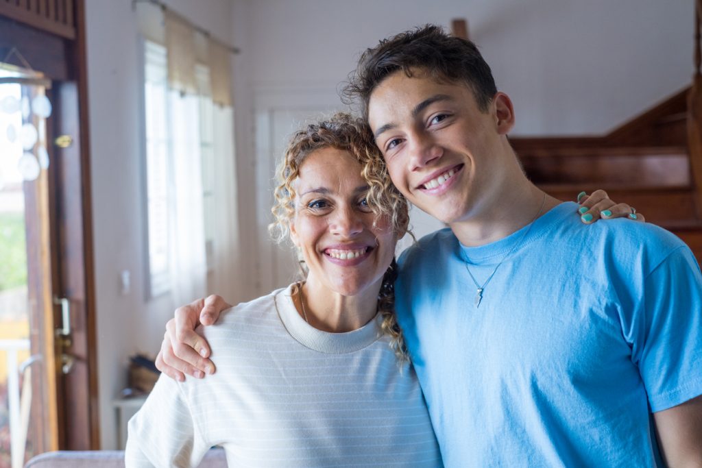 Mother and teen son side hugging and smiling