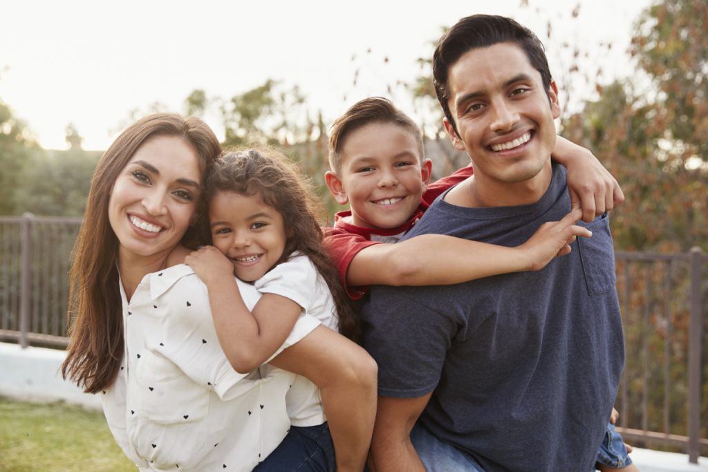 Young parents piggyback their children in the park