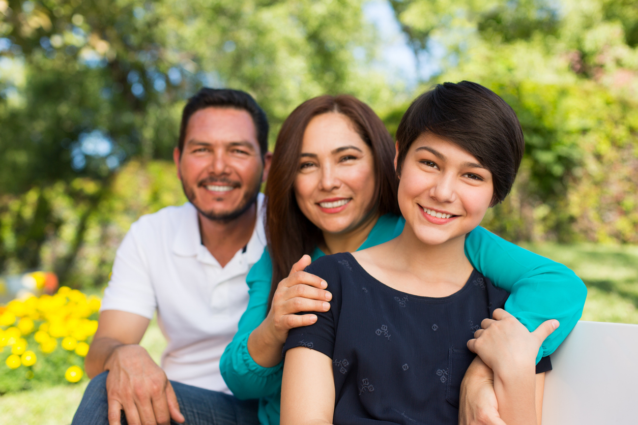 Happy teen girls and parents smiling together in a park