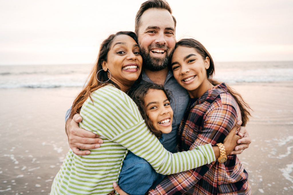 Family embracing for a photo at the beach