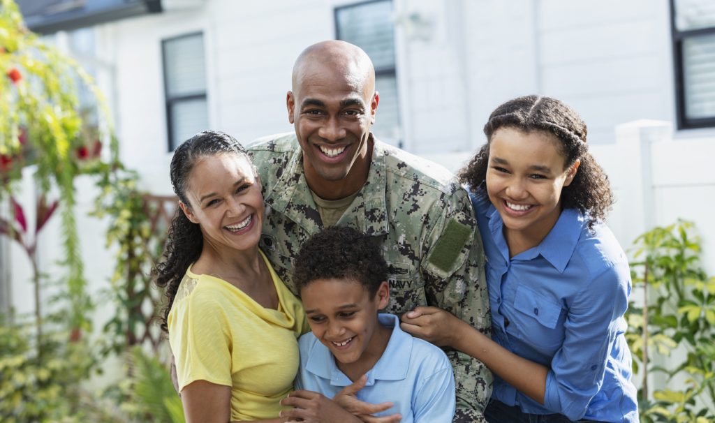 Military family smiling, posing for a photo. Dad in military uniform.