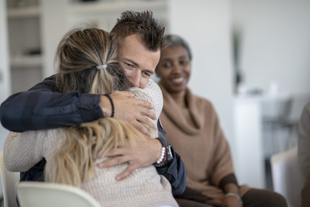 Man hugging his wife during substance abuse recovery program